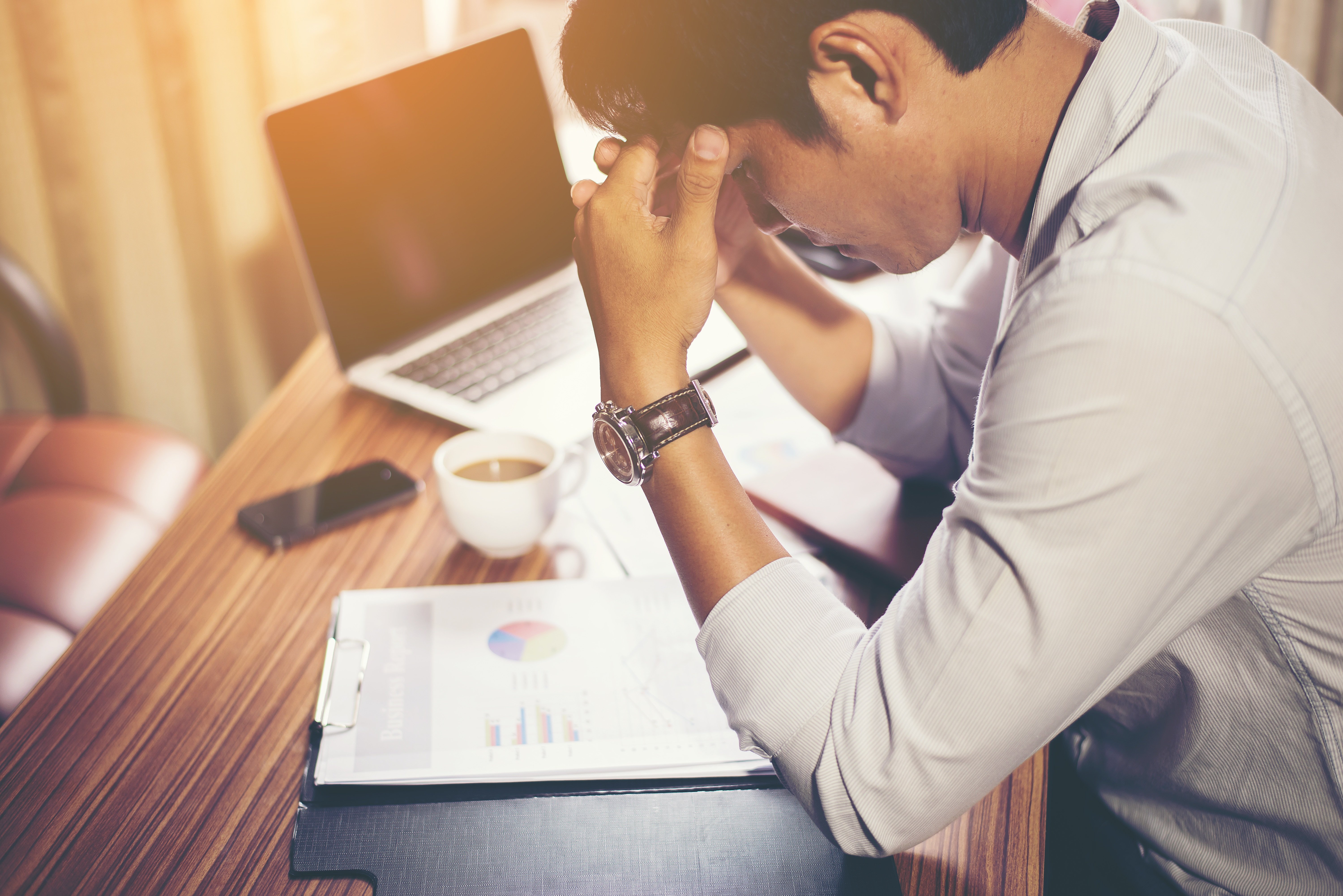 Canva - Man Holding His Head in front of Laptop