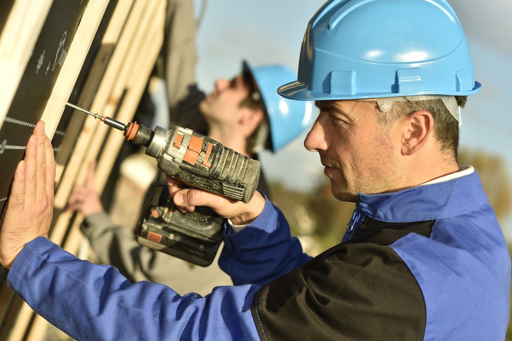 Construction worker using electric drill on building site