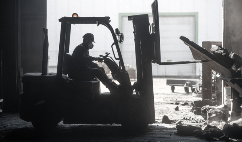 Man on forklift clearing construction debris